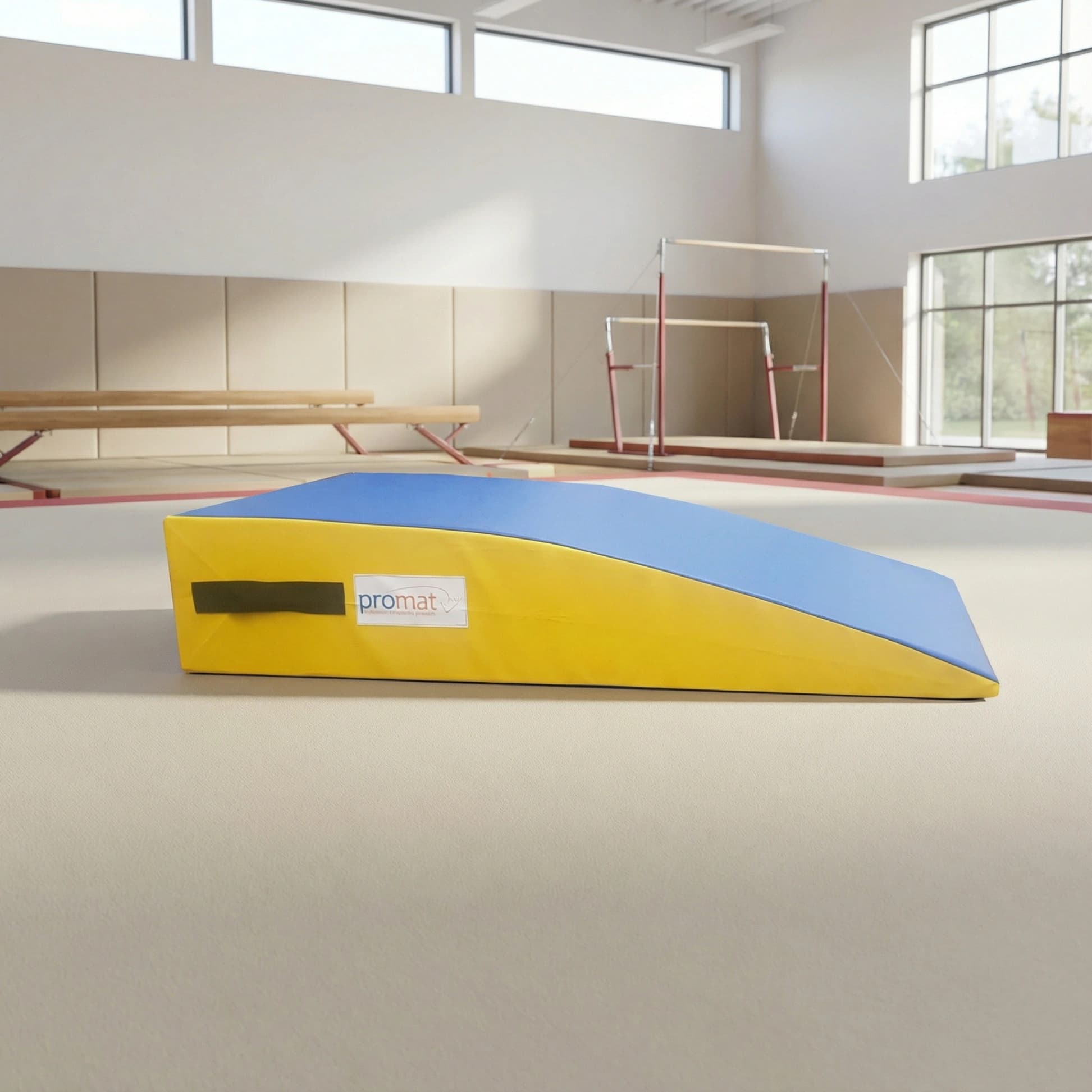 Foam springboard wedge with blue top and bottom and yellow sides, black carrying handle visible, placed on a gym floor near parallel bars.